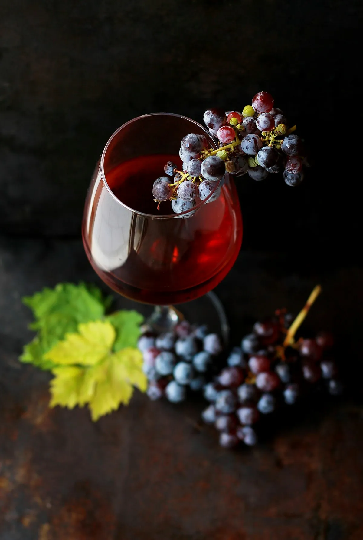 Glass of red wine with a cluster of estate grapes