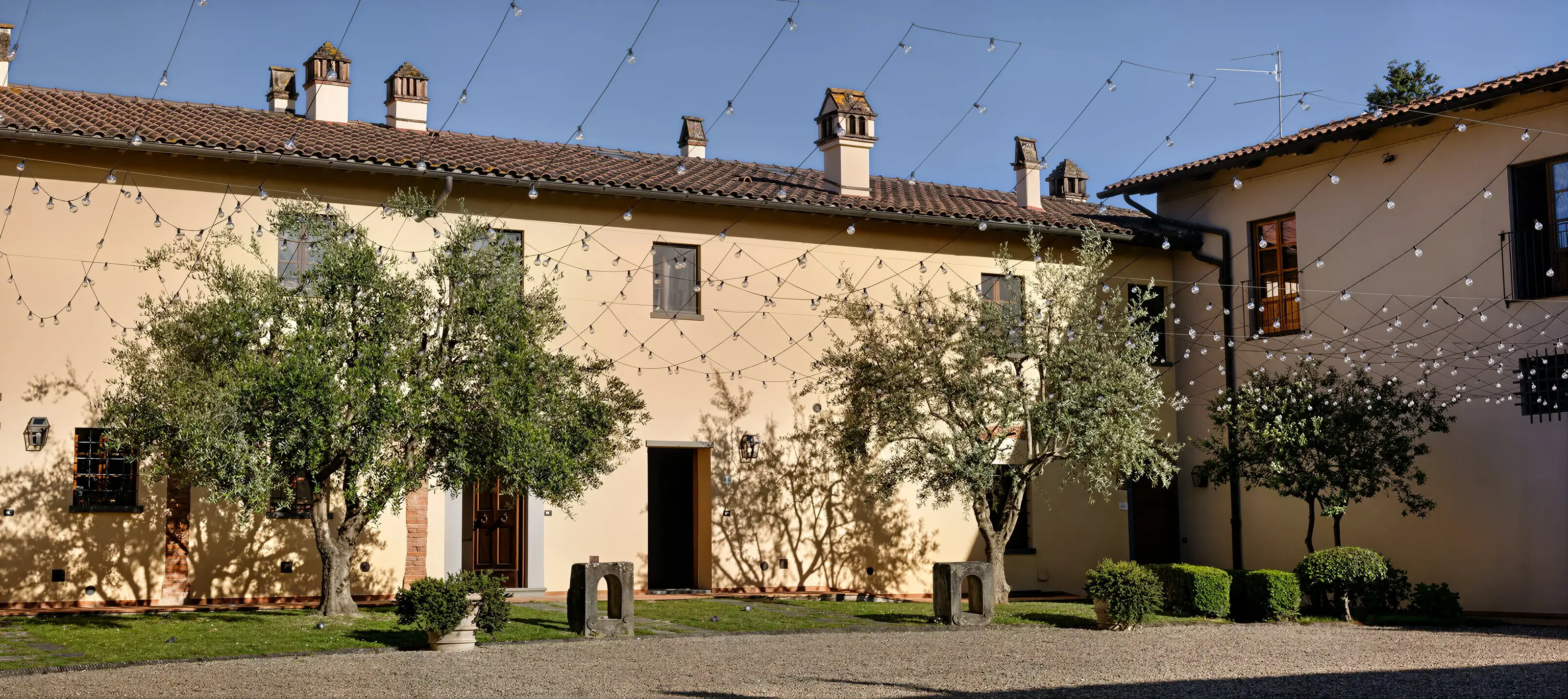 Il casolare del podere e la sua corte, con gli ulivi e le luci sospese fra i tetti