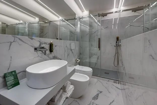 Il bagno della suite, in marmo bianco, con la doccia a filo e il lavabo ovale