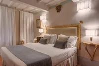 Il letto king-size sotto la cornice dorata, fra due appliques di stoffa
