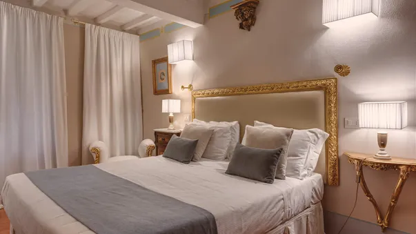 Il letto king-size sotto la cornice dorata, fra due appliques di stoffa